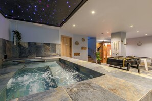 A spa area with a hot tub, a foosball table, and a ceiling with star projections.