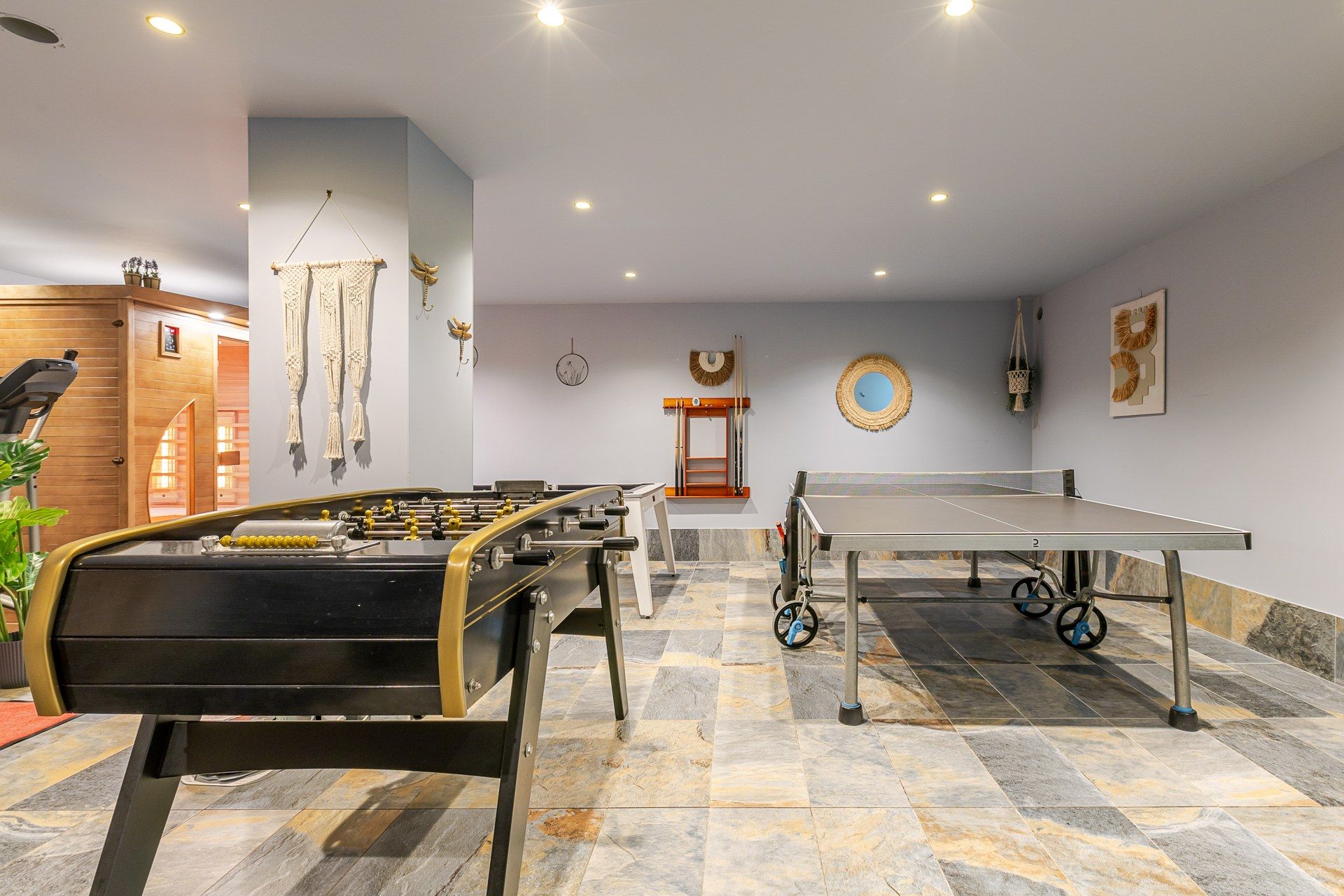 A room with a foosball table, ping pong table, and a wooden door.