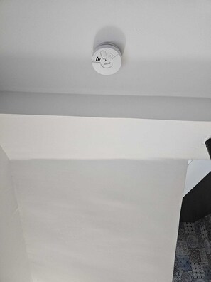 Eine Decke mit Rauchmelder und einer weißen Wand.