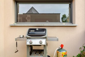 En Weber Spirit II-grill med en gastank och ett fönster ovanför.