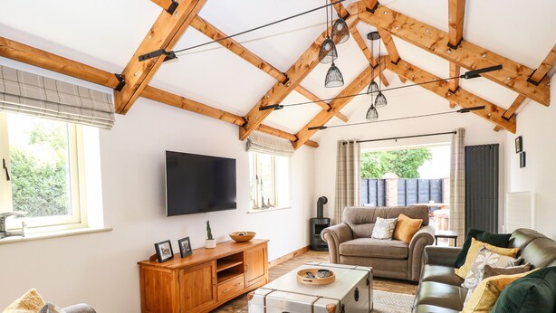 Un salon chaleureux avec un plafond en bois, un téléviseur à écran plat, un canapé, une causeuse et une cheminée.