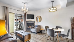 Un salon moderne doté d’une cheminée, d’un coin repas et d’une grande fenêtre agrémentée de rideaux.