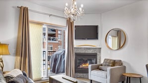 Un salon moderne doté d’une cheminée, d’un téléviseur fixé au mur et d’une porte-fenêtre coulissante donnant sur un balcon.