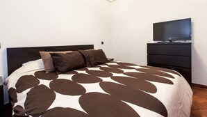 A bedroom with a bed, a television on a dresser, and a nightstand. - Luxury Flat in Madrid center (Madrid)