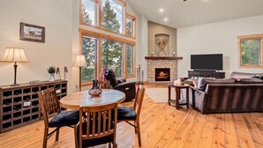 A spacious living room with a fireplace, a television, and a dining area with a wooden table and chairs.