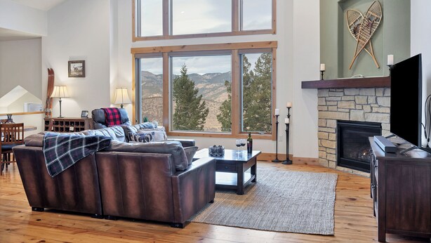A living room with a fireplace, large windows, and a stone wall.
