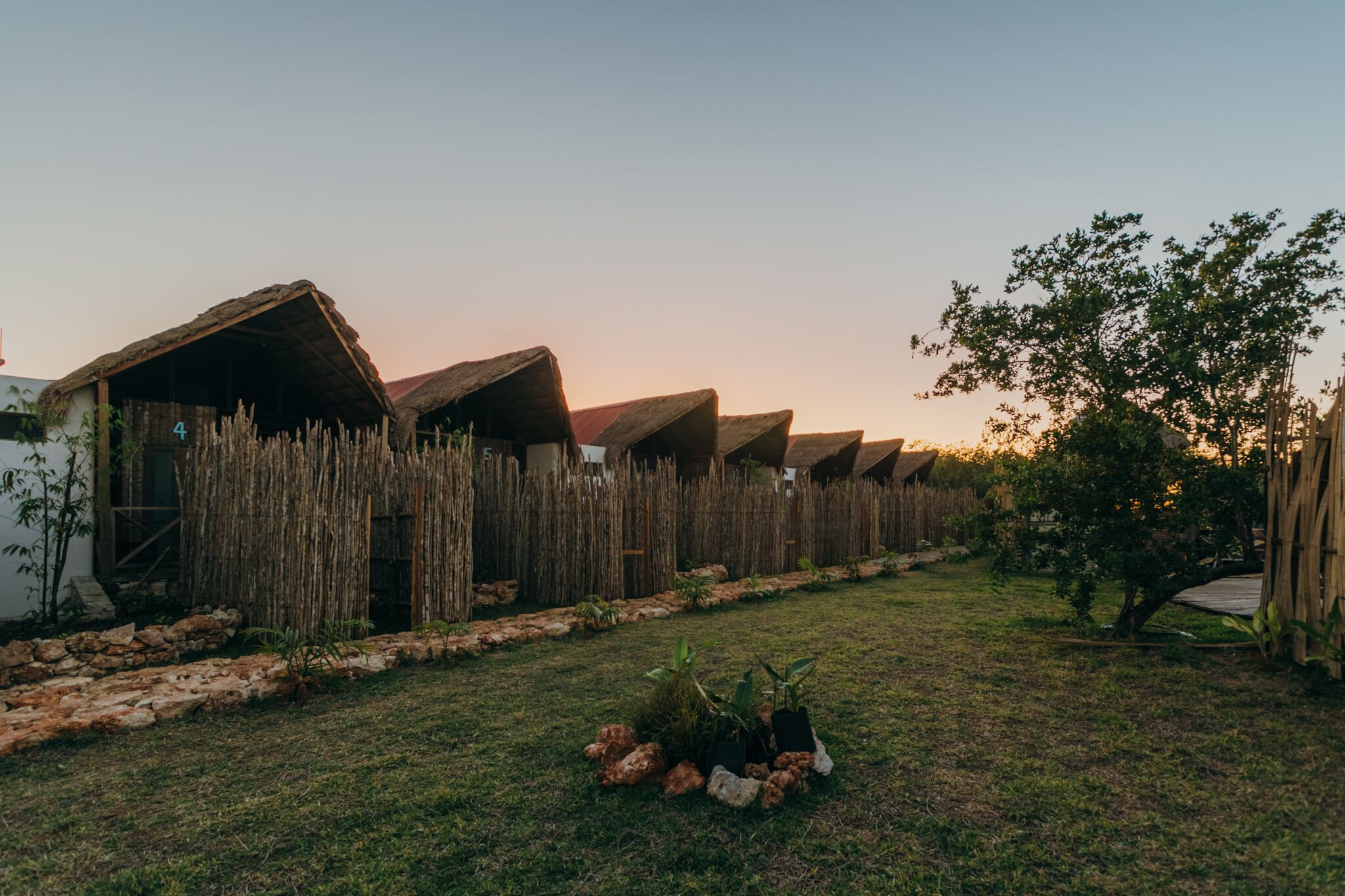 A row of thatched-roof huts with a stone pathway in between.