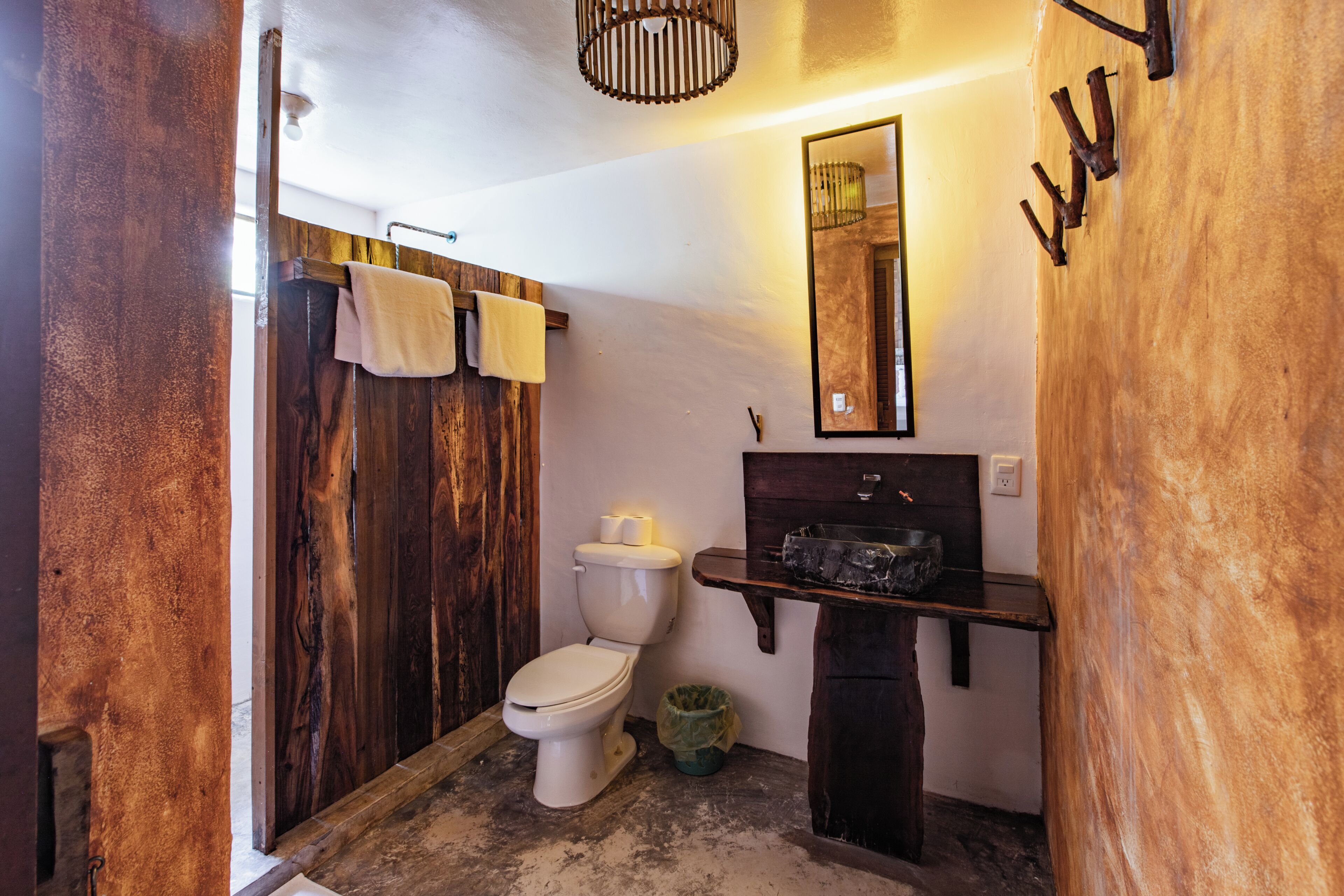 Un baño con cabina de ducha de madera, un inodoro, un lavabo y un espejo sobre él.