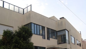 A modern building with a flat facade, large windows, and a tree in front. - Guida's place apartment (Porto)