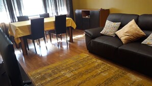 A living room with a sofa, a dining table with chairs, and a cabinet. - Guida's place apartment (Porto)