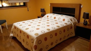 A room with a bed, two nightstands, a chair, and a window with blinds. - Guida's place apartment (Porto)