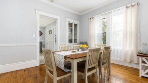 Un coin repas avec une table et des chaises en bois, un meuble blanc et une fenêtre avec des rideaux.