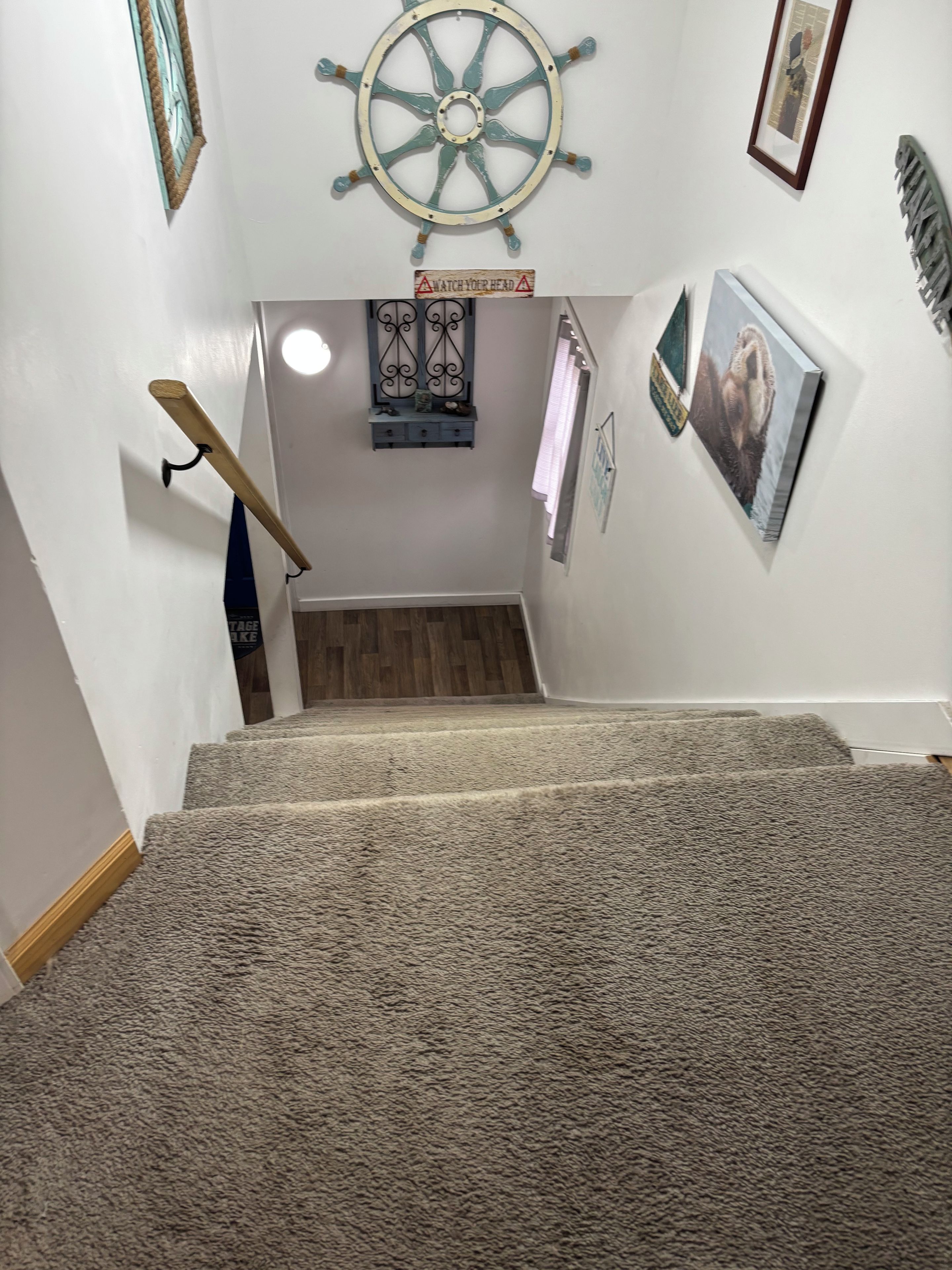 Una escalera alfombrada con un adorno de timón en la pared.