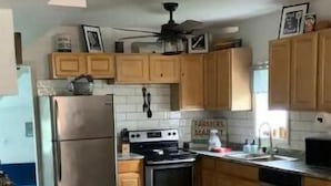 Een keuken met houten kastjes, een roestvrijstalen koelkast, een oven en een magnetron.