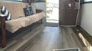 Ein gemütlicher Wohnbereich mit einer Couch, einem Holztisch und Blick durch eine Glastür auf eine Terrasses.
