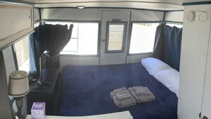 Ein kleines Schlafzimmer mit einem Einzelbett, einem kleinen Tisch und einem Fenster mit Vorhängen.