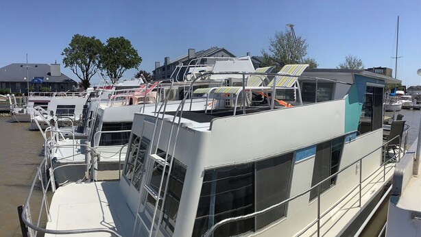 Ein Boot mit überdachtem Deck, einer Kabine mit Fenstern und einer Kettenbarriere.