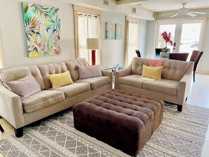 Relax in this stylish living room with a large sofa, ottoman, and dining area.
