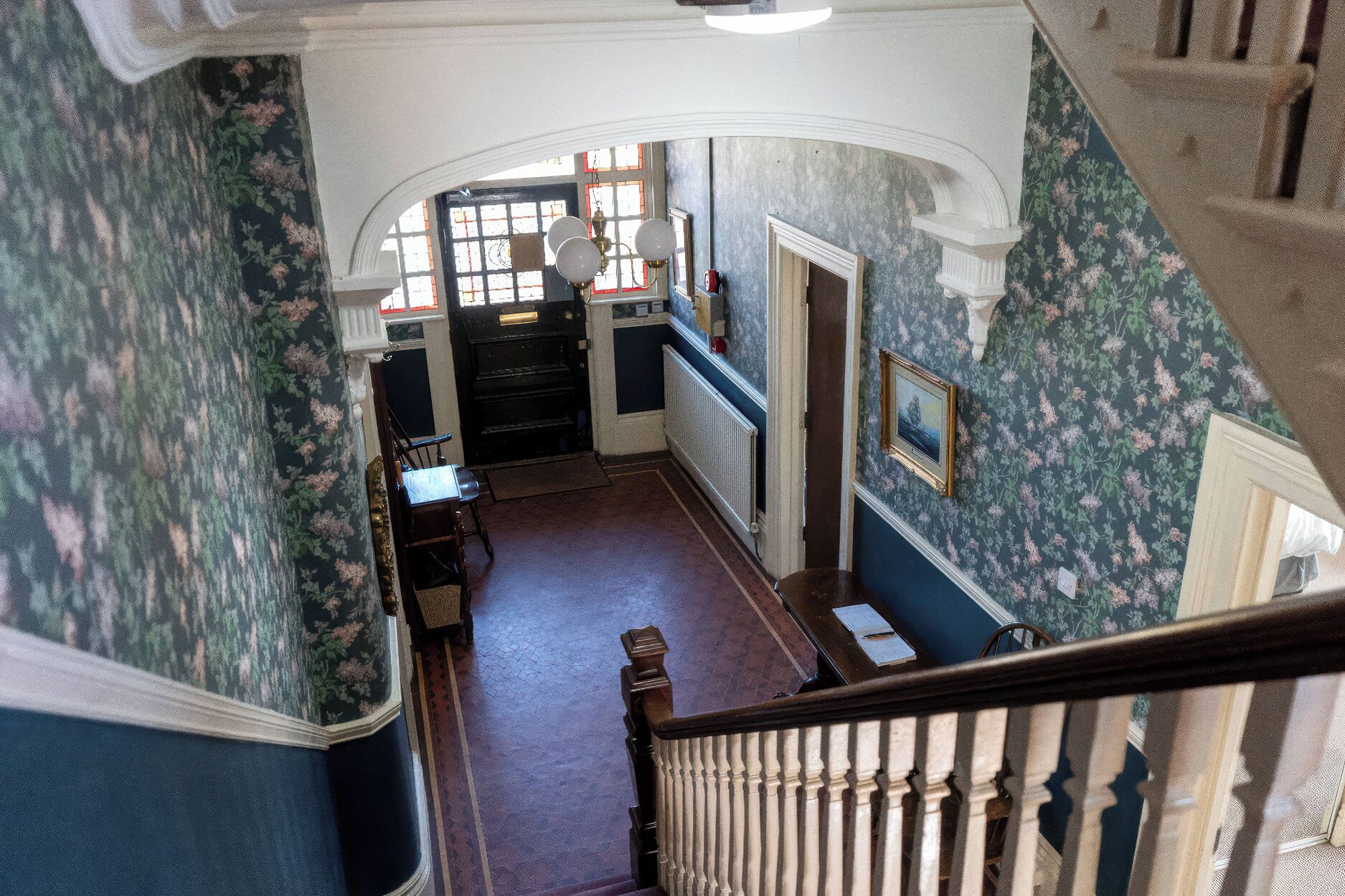 A hallway with a staircase, a radiator, and a door leading to another room.