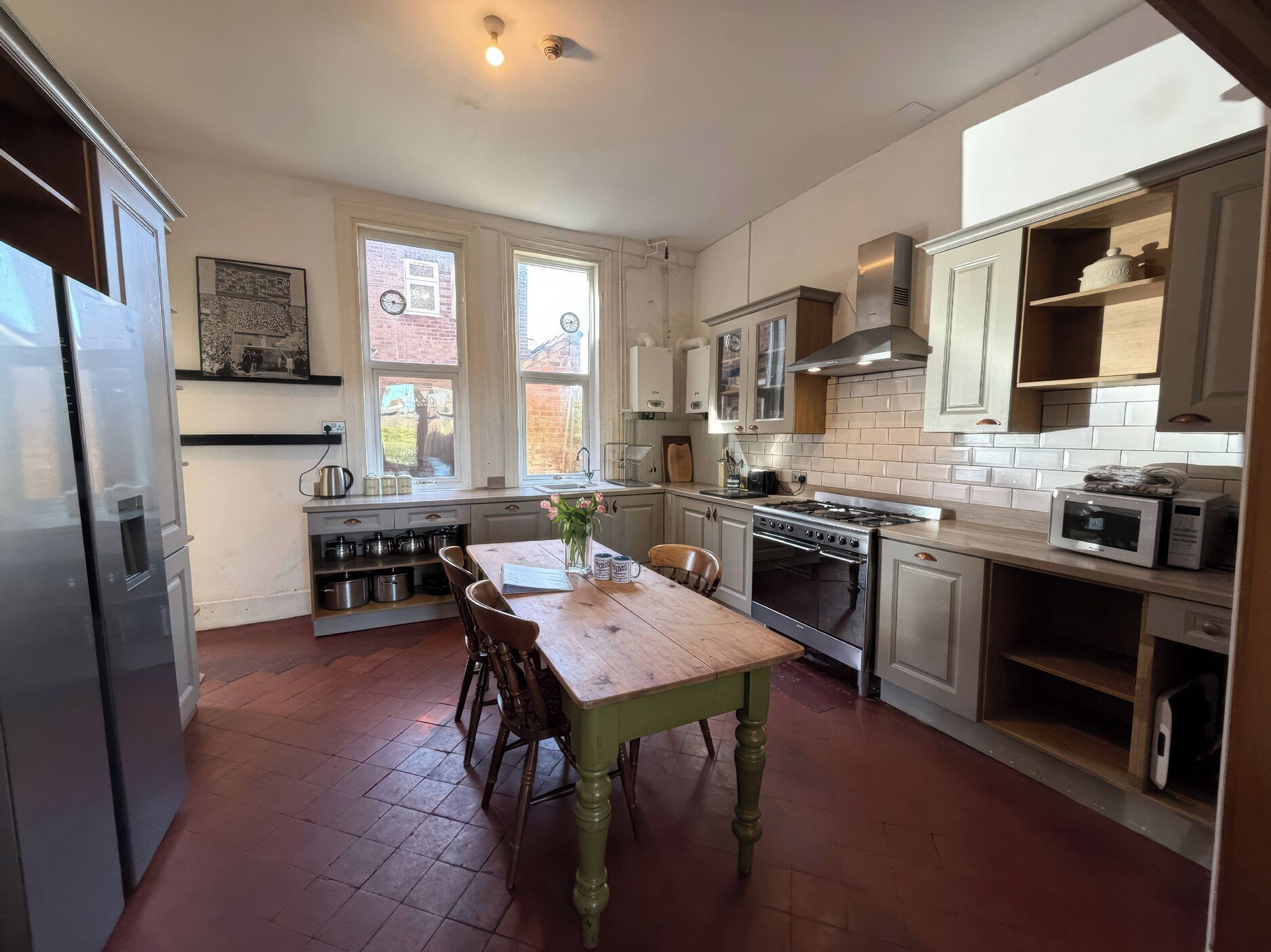 Une cuisine avec une table en bois, des placards, une cuisinière et un réfrigérateur.