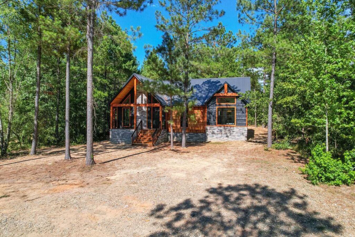 A cabin with a stone foundation, wooden exterior, and a porch with a staircase.