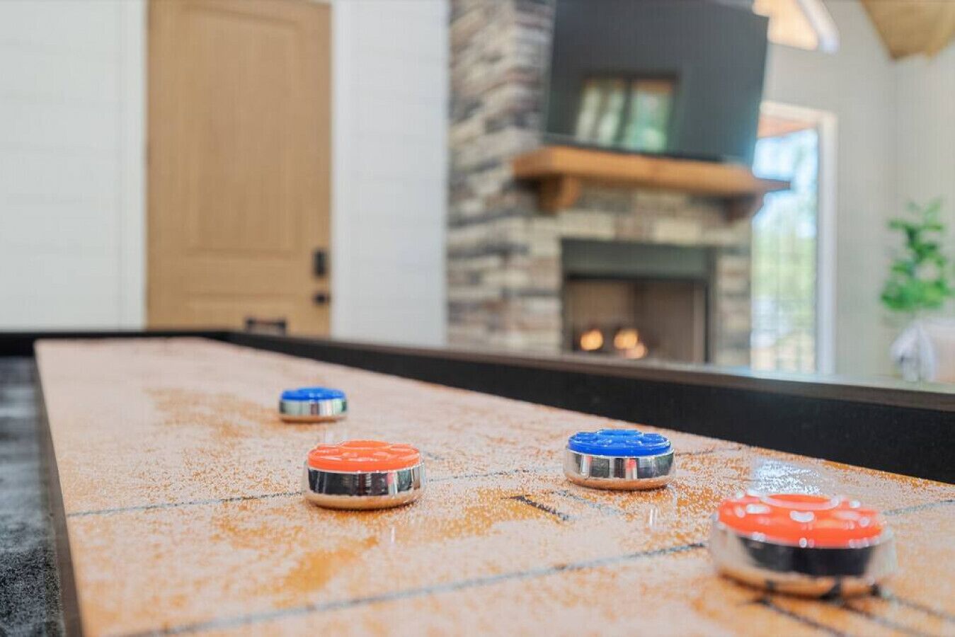 A shuffleboard table with pucks in red, blue, and orange.