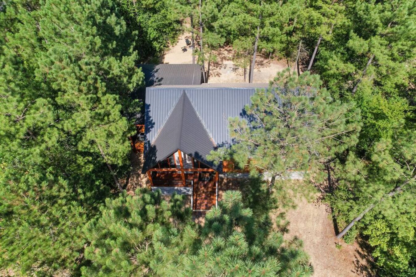An aerial view of a cabin surrounded by dense pine trees.