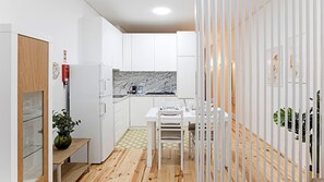 Una cocina moderna con armarios blancos, un salpicadero de mármol y un comedor con una mesa y sillas blancas.