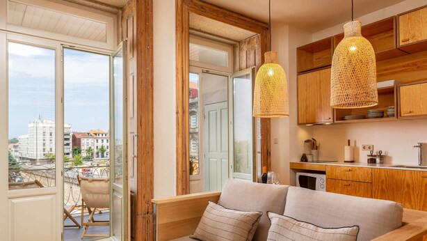 Un salon moderne avec un canapé, un banc en bois et un coin repas doté de meubles de rangement en bois et de luminaires suspendus.