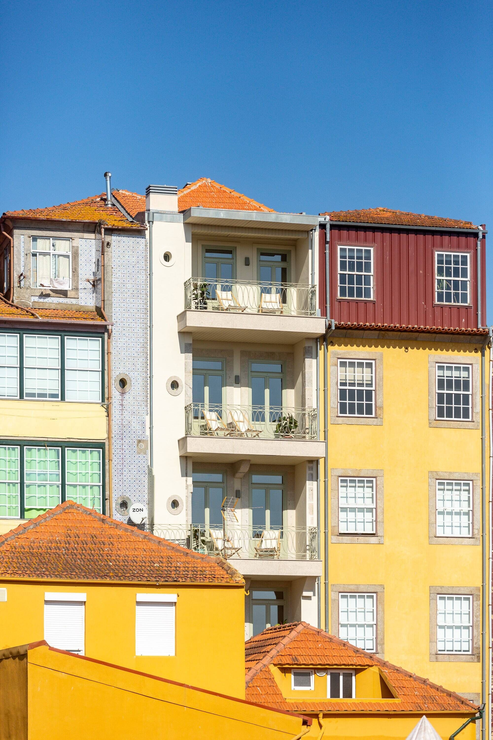 A multi-story building with balconies, a mix of window styles, and a red-tiled roof.
