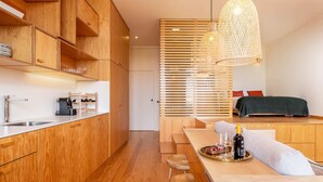 Une cuisine moderne avec des meubles en bois, un coin repas comprenant une table et des chaises, et un grand luminaire suspendu.