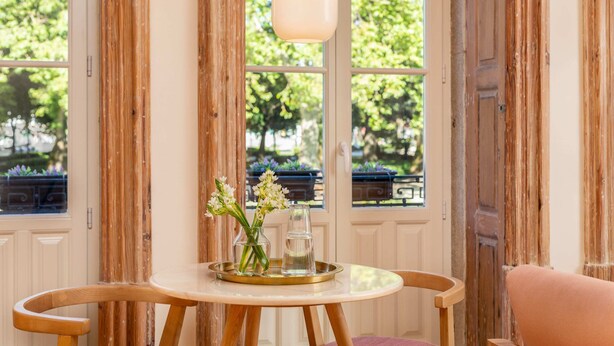 Une table en bois avec un plateau, un vase de fleurs et un verre.
