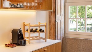Una cucina con macchina del caffè, portabottiglie e bicchieri sugli scaffali.