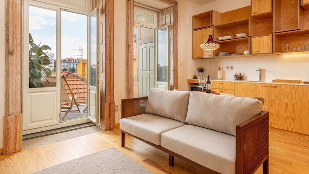 Een moderne woonkamer met een bank, houten kasten en een schuifdeur naar een balkon.