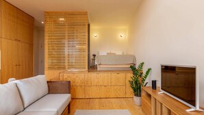 Een moderne woonkamer met een bank, houten kasten, een televisie en een plant.