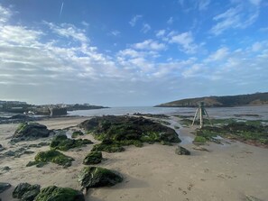 Ein Strand mit Felsen und einem Teleskop auf einem Stativ.