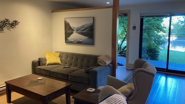 Una sala de estar moderna con un sofá gris, una mesa de centro y un cuadro de un paisaje montañoso.