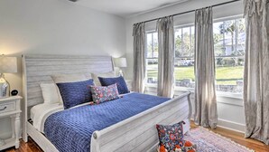 A bedroom with a bed, nightstands, a ceiling fan, and a view of the outdoors.
