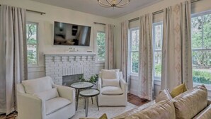 A living room with a fireplace, a television mounted above it, and a sofa.