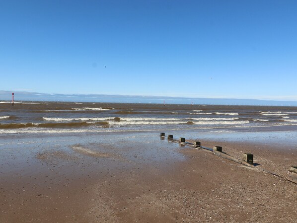 A beach with a wooden jetty and waves. - Ty Uchaf (Rhyl)