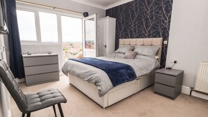 A bedroom with a bed, a chair, a dresser, and a nightstand. - Ty Uchaf (Rhyl)