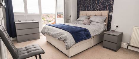 A bedroom with a bed, a chair, a dresser, and a nightstand.