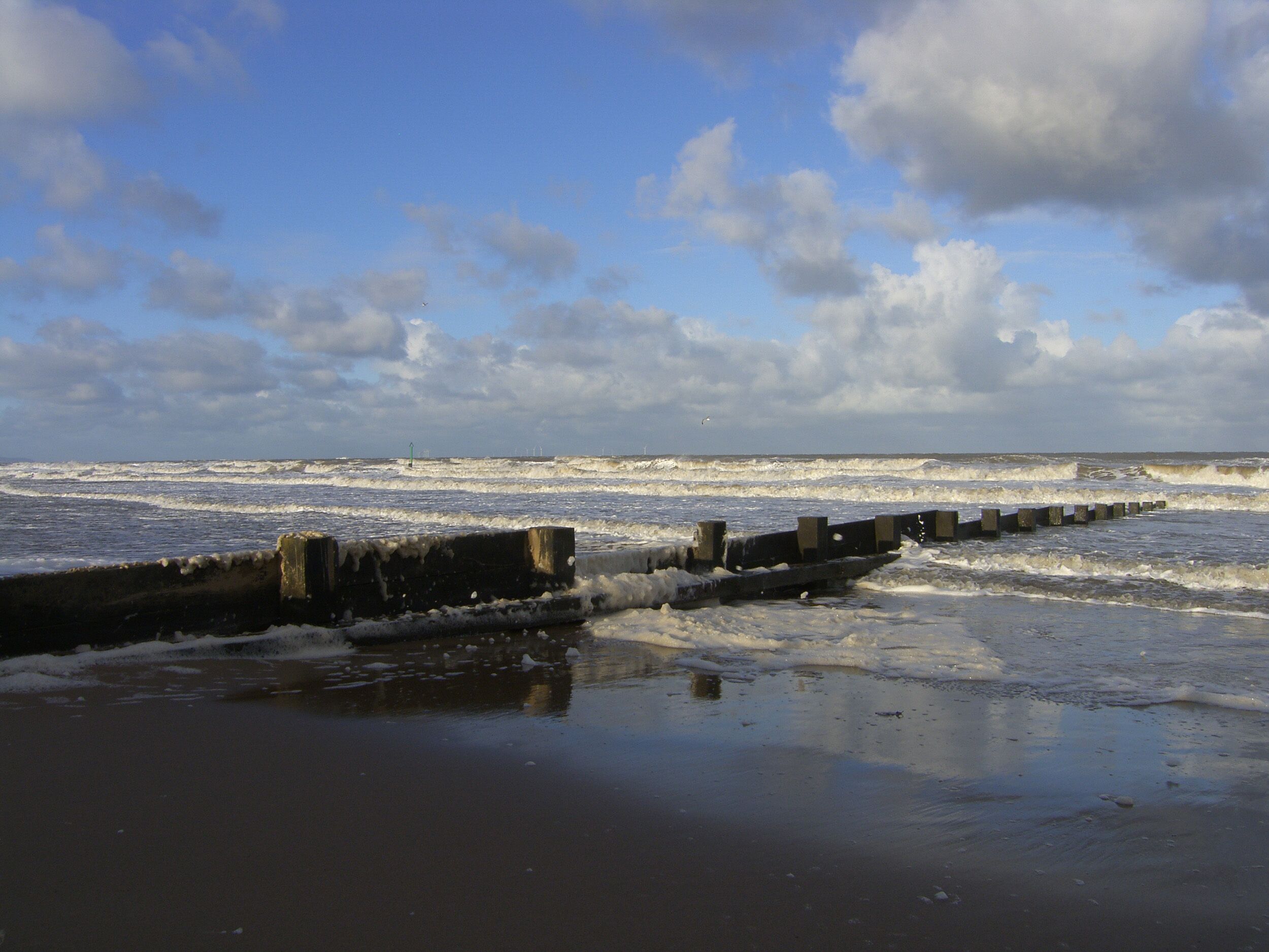 A beach with waves crashing onto a concrete sea wall.