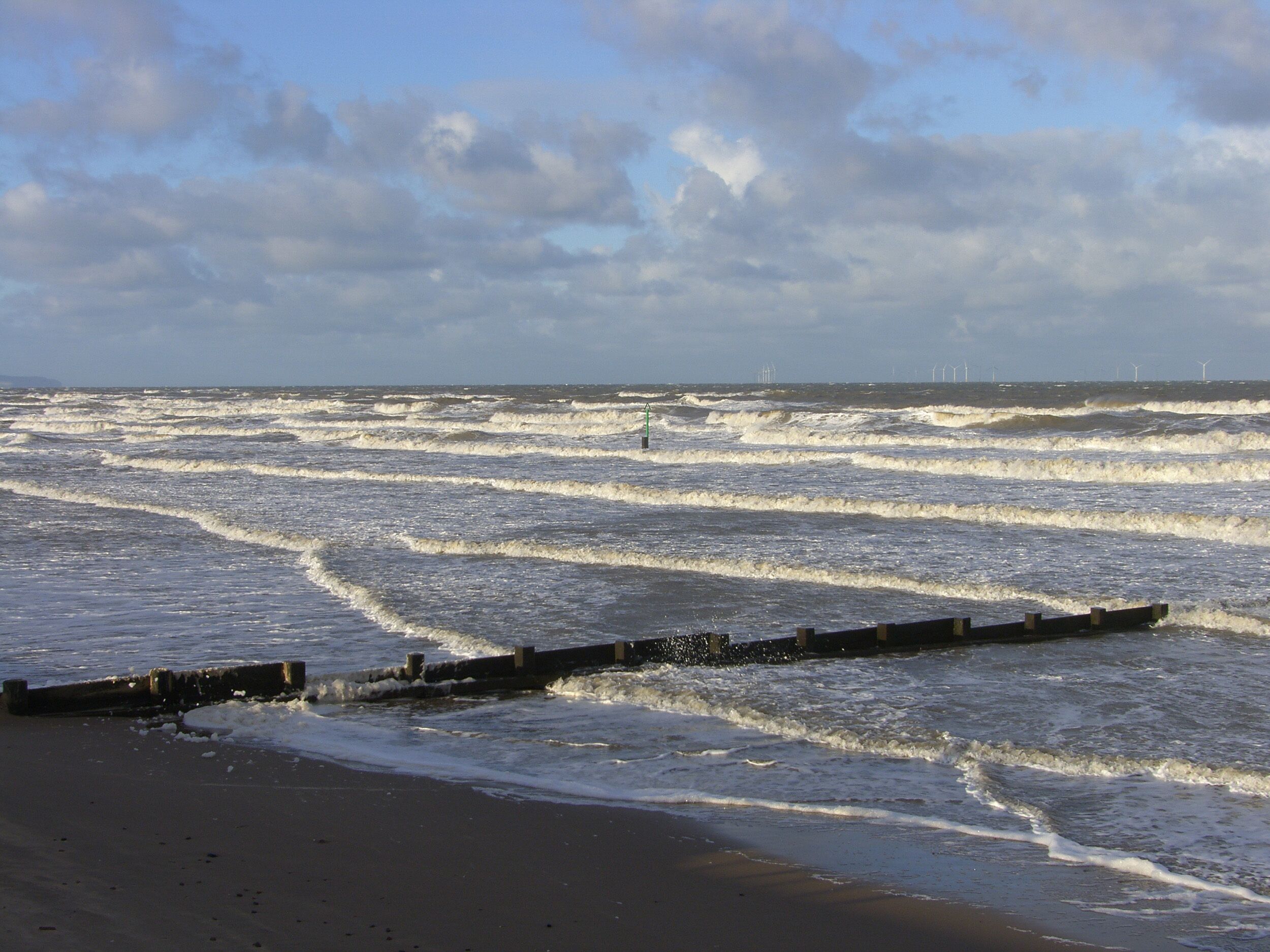 A beach with waves and a cloudy sky.