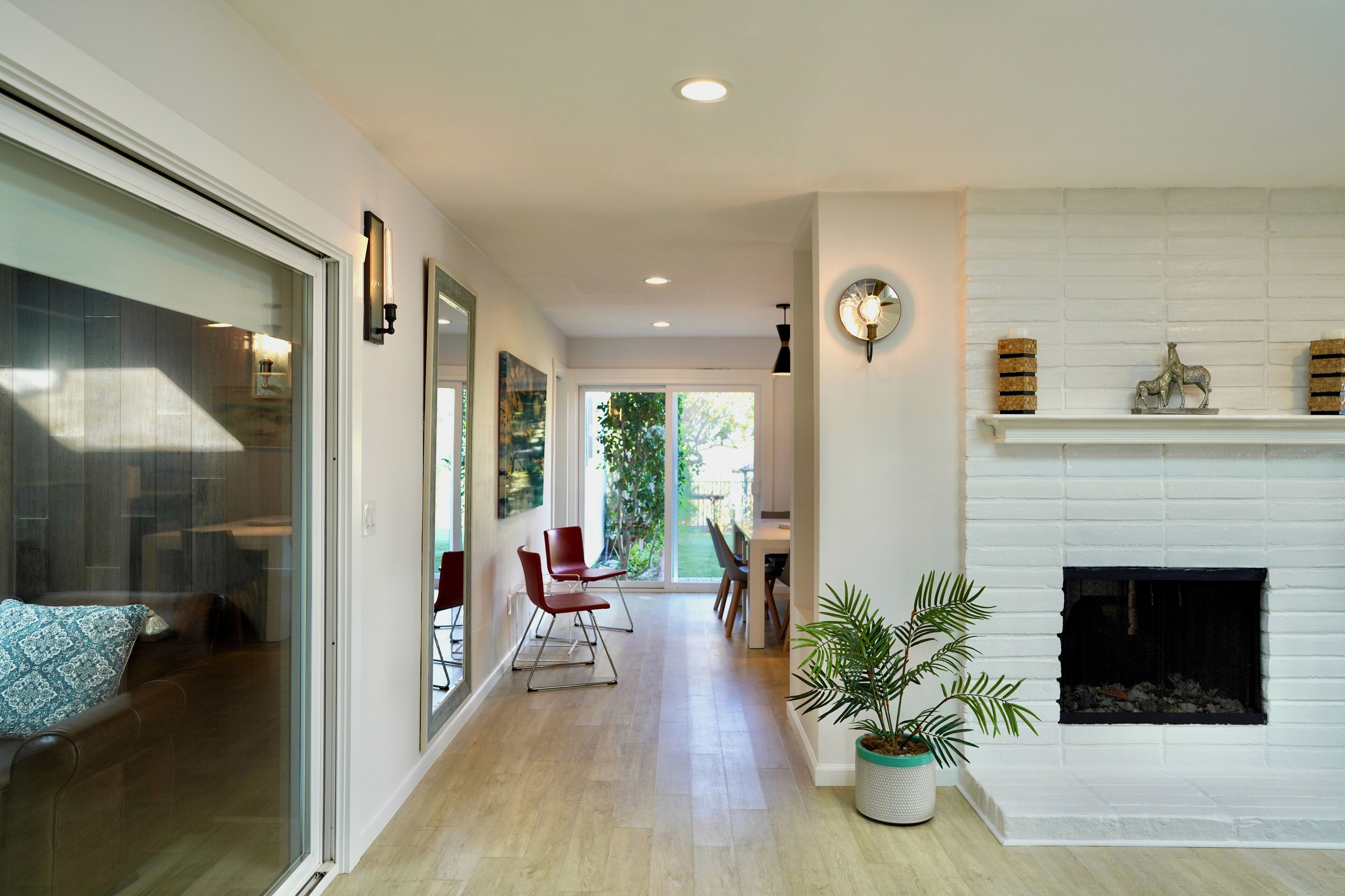 A modern interior with a fireplace, a dining area with chairs, and a potted plant.