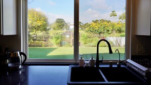 Eine Küche mit großem Fenster, Spüle und Wasserkocher.