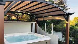 Ein Whirlpool unter einer Holzpergola im Garten.