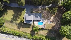 Vue aérienne d’une propriété résidentielle dotée d’une piscine, d’un garage indépendant et d’une allée.