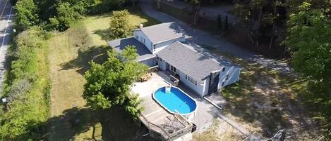 A residential property with a swimming pool, a covered patio, and a detached garage.