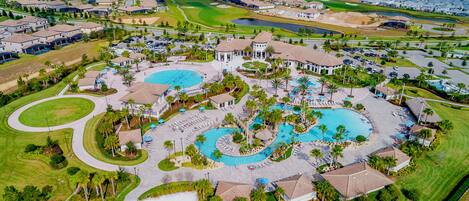 An aerial view of a resort with multiple swimming pools, a golf course, and residential buildings.